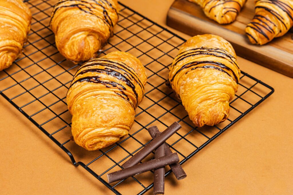 Croissant de chocolate | Pastelería Ciro Guatemala | Croissant artesanal elaborado con nuestra masa laminada especial a base de mantequilla importada, fermentado y horneado lentamente para lograr capas aireadas y doradas. Relleno con dos generosas barras de chocolate para un resultado indulgente en cada bocado.