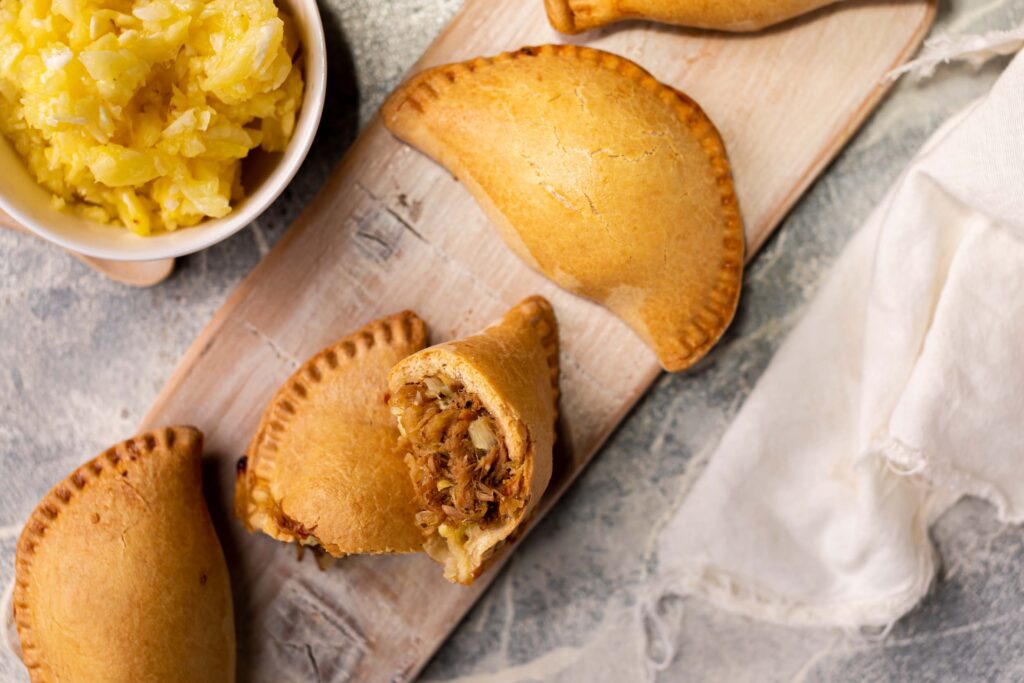 Empanada al pastor | Pastelería Ciro Guatemala | Empanada horneada con masa salada a base de mantequilla, rellena de pollo marinado al estilo al pastor: una mezcla de especias molidas en casa, piña natural y chile suave que dan como resultado un relleno jugoso y lleno de carácter. Tradición mexicana reinterpretada con el cuidado artesanal de Ciro.