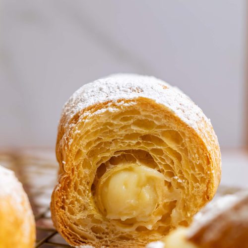 Cañoncitos | Pastelería Ciro Guatemala | Crujientes rollitos de hojaldre elaborado con mantequilla pura, rellenos con nuestro manjar de leche artesanal de textura sedosa. Finalizados con un delicado velo de azúcar glas, cada bocado es una combinación clásica de crujiente y dulce