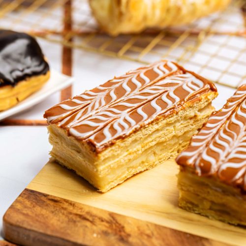 Napoléon | Pastelería Ciro Guatemala | Elegante pastel napoleón de capas crujientes de hojaldre horneado con mantequilla, intercaladas con suave manjar de leche y coronadas con una cobertura de cajeta artesanal de profundo sabor acaramelado. Una pieza de repostería clásica con carácter.