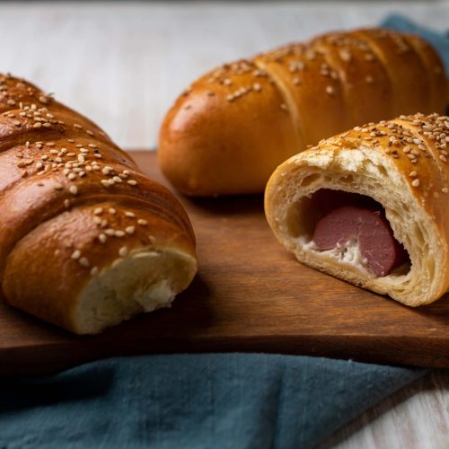 Sabanita | Pastelería Ciro Guatemala | Delicada y deliciosa, nuestra sabanita salada está elaborada con una suave masa horneada a la perfección rellena con salchicha de pavo y un cremoso toque de queso crema que se funde en cada bocado. Decorada con ajonjolí para un acabado crujiente y aromatico, es el equilibrio ideal entre sabor y textura.