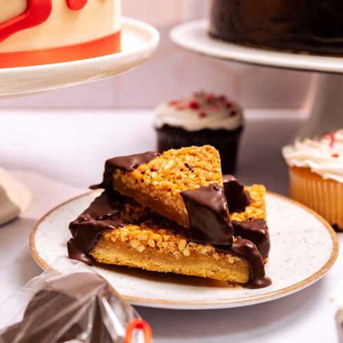 Porción piquete | Pastelería Ciro Guatemala | Triángulo de galleta crujiente cubierto con caramelo artesanal, chocolate Ghirardelli de calidad superior y maníes tostados. Una pieza pequeña e irresistible de dulce y salado que celebra la combinación de texturas y sabores intensos.