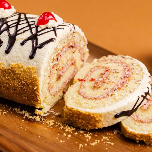 Brazo de Vainilla | Pastelería Ciro Guatemala | Clásico brazo gitano de bizcocho de vainilla suave, relleno con mermelada de fresa y cubierto de crema de vainilla. Una pieza de pastelería clásica y reconfortante que nunca decepciona.